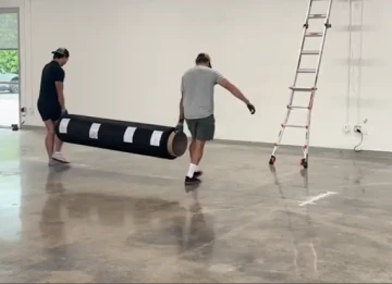 ロール状のコートマットを運ぶ様子